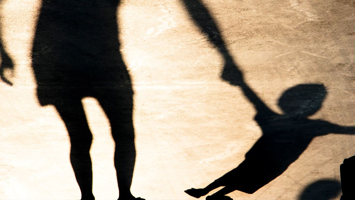 A silhouette of a child holding an parent's hand | Photo: AlexLinch/iStock