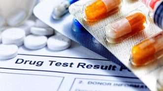 drug test results with a stack of pills on top of them | Keng Po Leung / Dreamstime.com