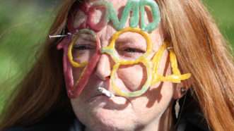 Protester in Scotland with COVID-1984 in gummies on her face | Andrew Milligan/ZUMA Press/Newscom