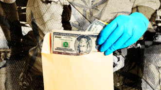 money in an envelope held by gloved hands representing asset forfeiture | Illustration: Lex Villena; Photographerlondon / Dreamstime.com