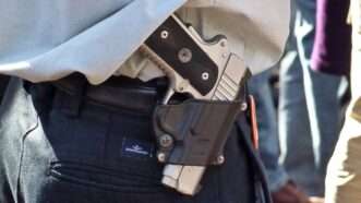 A handgun holstered and being carried unconcealed