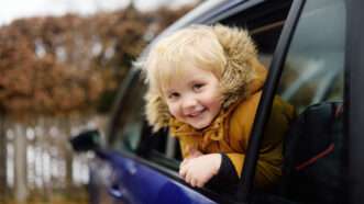 Child leans out the window of a car