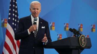 President Joe Biden speaking on stage holding a microphone