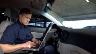 Cop in car operating laptop