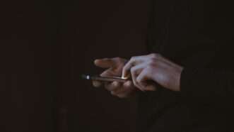 hands on dark background flipping through cellphone