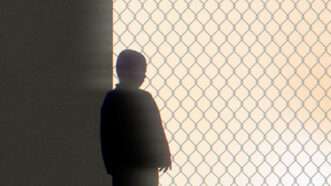 Silhouette of a child behind a chain link fence