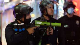 A police officer with the Los Angeles Police Department aims non-lethal projectiles into a crowd