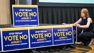 Woman putting up 'Vote No' signs in Kansas to "stop the ban" on abortion