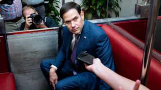 Senator Marco Rubio sits on a transport car under the United States Capitol, surrounded by reporters