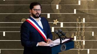 Chilean President Gabriel Boric speaking at a podium with a red, white, and blue sash over his suit. A photoshopped background image shows a ballot for the 1980 constitutional referendum. | Illustration Lex Villenas: Lucas Aguayo Araos/ZUMAPRESS/Newscom; Wikimedia