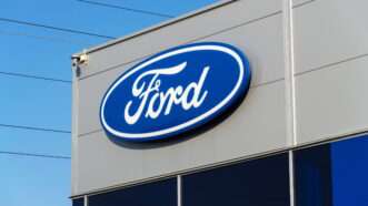 Ford Motor Co. logo on the outside of a franchised dealership. | Photo 100895521 © Josefkubes | Dreamstime.com