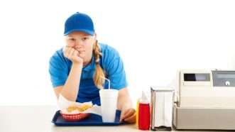 Fast food worker leans over counter