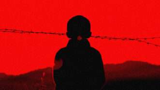 A child stands in front of barbed wire and a red background