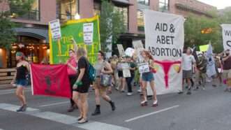 pro-choice protesters with sign that says "aid and abet abortion" | Jim Max/ZUMAPRESS/Newscom