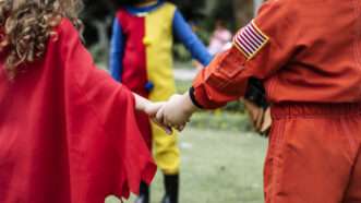 Kids in Halloween costumes holding hands.