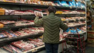 An elderly woman looks at meat prices while shopping in September 2022