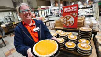 A grocery store worker is seen holding a pumpkin pie