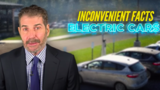 John Stossel stands in front of a row of vehicles while discussing "inconvenient facts about electric cars"