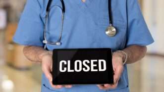 Doctor holding "Closed" sign