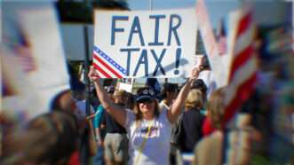 A protester holds up a sign reading "FAIR TAX!"