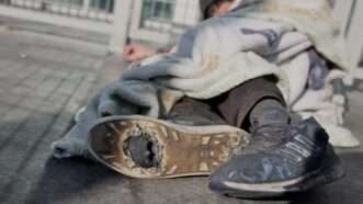 Unhoused person sleeping on a sidewalk | Xin Hua / Xinhua News Agency/Newscom