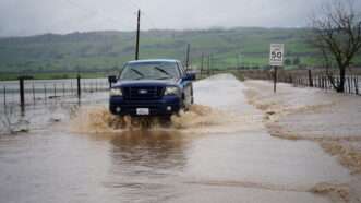 truck drives through muddy flood waters