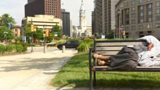 A homeless man sleeps on a bench near Philadelphia's city hall. Poverty urban rural Pennsylvania taxes state government welfare