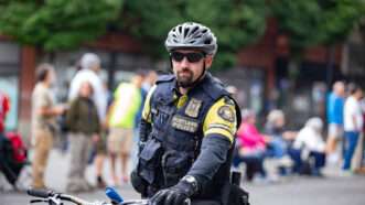 A Portland, Oregon, police officer on a bicycle in the midst of a public event.