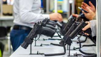 An unidentified shopper peruses a row of handguns for sale.