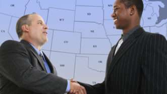 Two businessmen shaking hands in front of a blue and grey map of the United States. | Photoeuphoria | Dreamstime.com