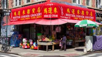 A corner grocery store in New York City's Chinatown neighborhood, with a bright red awning. | John Penney | Dreamstime.com