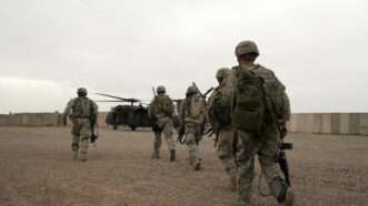 American soldiers in Iraq file in the direction of a helicopter.
