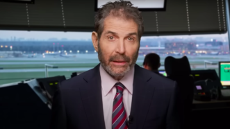 John Stossel is seen in front of an air traffic control system | Stossel TV