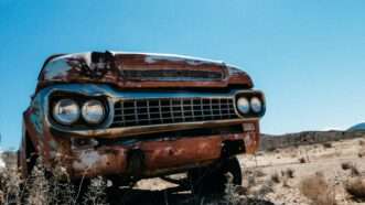 a rusty car sits in a deserted area