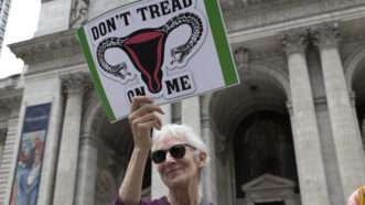 protester holding sign with uterus that says "don't tread on me"