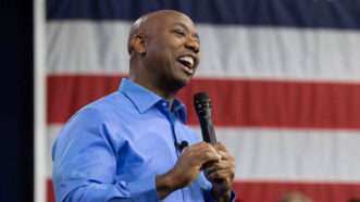 Tim Scott standing in front of an American flag, holding a microphone, and looking optimistic. | Joshua Boucher/TNS/Newscom