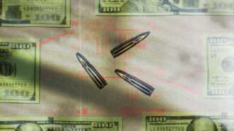Long-range rifle rounds against the backdrop of U.S. 0-bills and a diagram of a rifle.