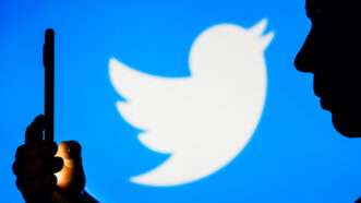 person looking at phone in front of the Twitter logo | Rafael Henrique/ZUMAPRESS/Newscom