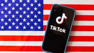 TikTok app on phone in front of American flag | Stanislav Kogiku/ZUMAPRESS/Newscom