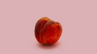 A red-toned peach on a pink background | Charles Deluvio/Unsplash
