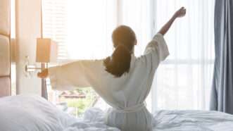 A woman wakes up in a hotel room and stretches. | Noipornpan | Dreamstime.com
