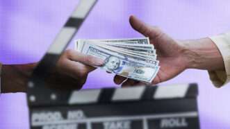 Hands exchange a wad of cash against a backdrop of a clap board.