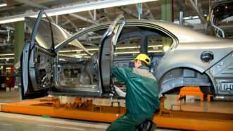 An automotive assembly line worker building a sedan.