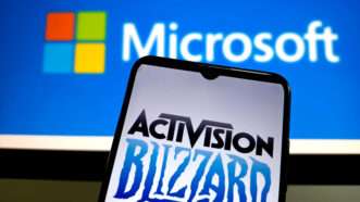 Activision Blizzard logo on phone in front of screen with Microsoft logo