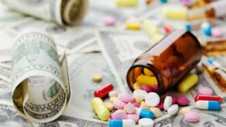 A roll of cash next to a spilled bottle of pills | Julia Sudnitskaya | Dreamstime.com