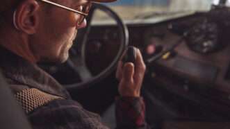 Over-the-shoulder shot of a trucker speaking into his CB radio. | Welcomia | Dreamstime.com
