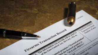 A pen and a bullet on top of a federal firearm transaction record. | Guy Sagi | Dreamstime.com