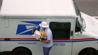 A USPS mail carrier loading packages into a mail truck. | Kilmermedia | Dreamstime.com