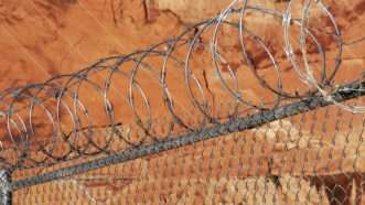 Chain-link fence topped with razor wire. | Jim Parkin | Dreamstime.com