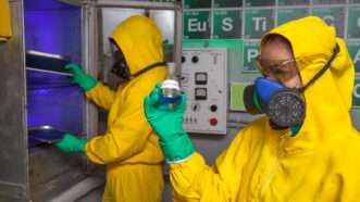 Two scientists in Hazmat suits cook methamphetamine in a laboratory. | DPST/Newscom